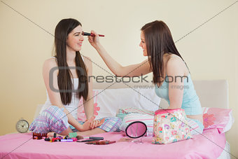 Smiling girl giving her friend a makeover at sleepover