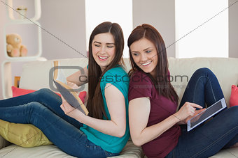 Girl showing her friend her book on the sofa