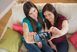 Two friends on the couch taking a selfie with smartphone