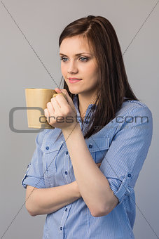 Pensive pretty brunette holding cup of coffee
