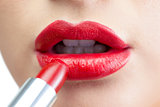 Extreme close up on gorgeous red lips being made up