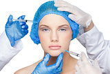 Surgeons making injection on pretty blonde wearing blue surgical cap