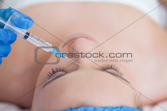 Surgeon making injection on pretty woman lying