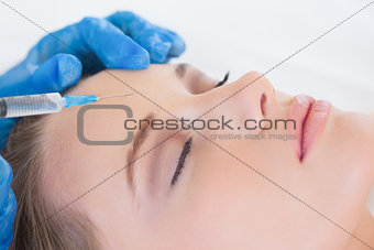 Surgeon making injection on womans forehead