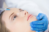 Surgeon making injection on forehead on calm woman lying