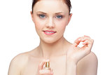 Smiling nude model spraying perfume on her wrist