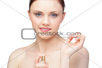 Smiling nude model spraying perfume on her wrist