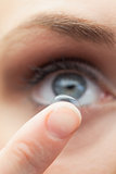 Extreme close up on cute model applying contact lens