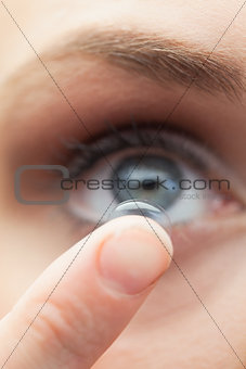 Extreme close up on cute model applying contact lens