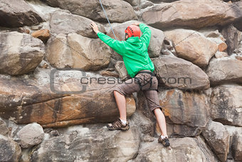 Determined man scaling a huge rock face