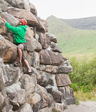 Focused man ascending a large rock face