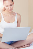 Content brunette sitting on bed using her laptop