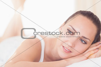 Smiling brunette lying on bed and thinking
