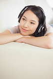 Content asian girl lying on the sofa and listening to music
