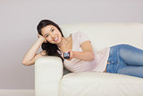 Cheerful asian girl lying on the couch watching tv