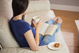 Young woman holding her coffee and reading book