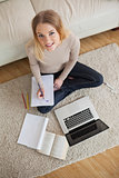 Happy woman doing homework and sitting on floor using laptop