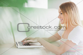 Happy woman sitting on floor using laptop