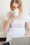 Woman drinking coffee while using laptop