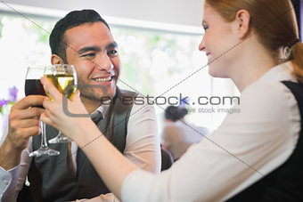 Smiling business partners clinking wine glasses