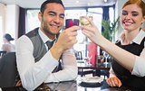 Smiling business partners clinking wine glasses looking at camera