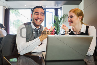 Laughing business people working on laptop