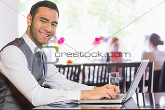 Smiling businessman working on laptop