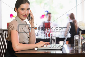 Businesswoman calling on phone using laptop