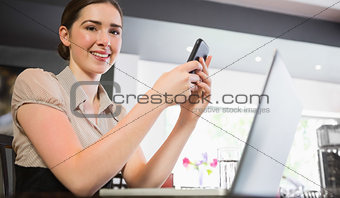 Smiling businesswoman holding phone looking at camera