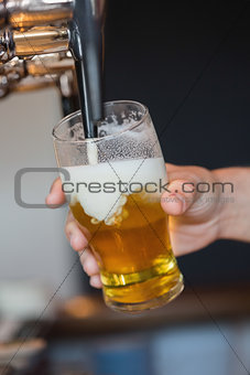 Hand holding glass filling beer
