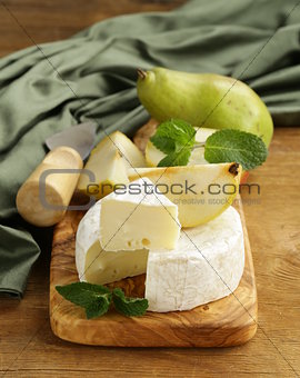 soft brie cheese (camembert) with pears on a wooden board