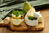 soft brie cheese (camembert) with pears on a wooden board