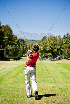 Golf player performs a tee shot