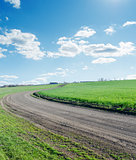 winding rural road under blue cloudy sky