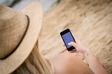 Woman sat on the beach using a mobile phone