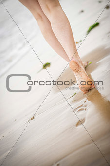 Woman's legs walking along the beach