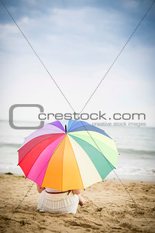 Woman sat on the beach with umbrella