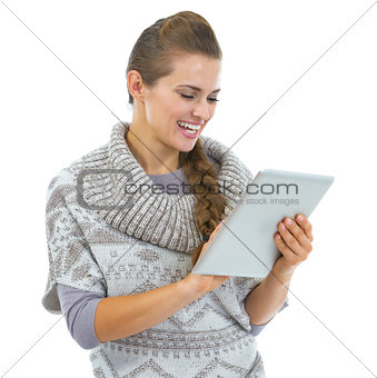 Happy young woman in sweater and christmas hat using tablet pc