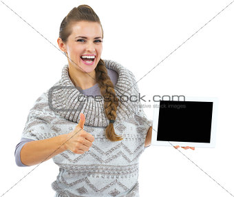Smiling young woman in sweater and christmas hat with tablet pc 