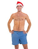 Smiling man in beach shorts and santa hat