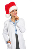 Happy doctor woman in santa hat looking on copy space