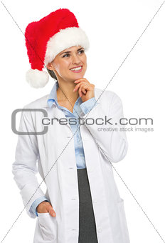 Happy doctor woman in santa hat looking on copy space