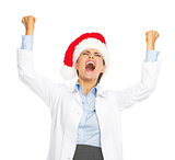 Happy doctor woman in santa hat rejoicing success