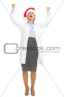 Full length portrait of happy doctor woman in santa hat rejoicin