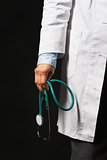 Closeup on stethoscope in hand of doctor woman on black backgrou