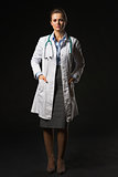 Full length portrait of doctor woman isolated on black