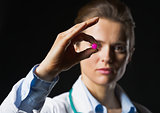 Closeup on pill in hand of doctor woman on black background