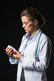 Doctor woman looking on medicine bottle on black background