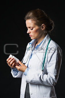 Doctor woman looking on medicine bottle on black background