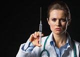 Serious doctor woman with syringe isolated on black